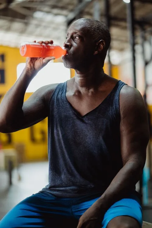 Active consumer drinking an orange hydration beverage after exercise